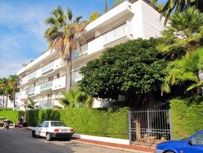 A multi-story residential building with balconies, surrounded by lush greenery and palm trees. - Homerez - Apartment in Antibes (Antibes)