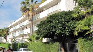 A multi-story building with balconies, surrounded by lush greenery and palm trees. - Homerez - Apartment in Antibes (Antibes)