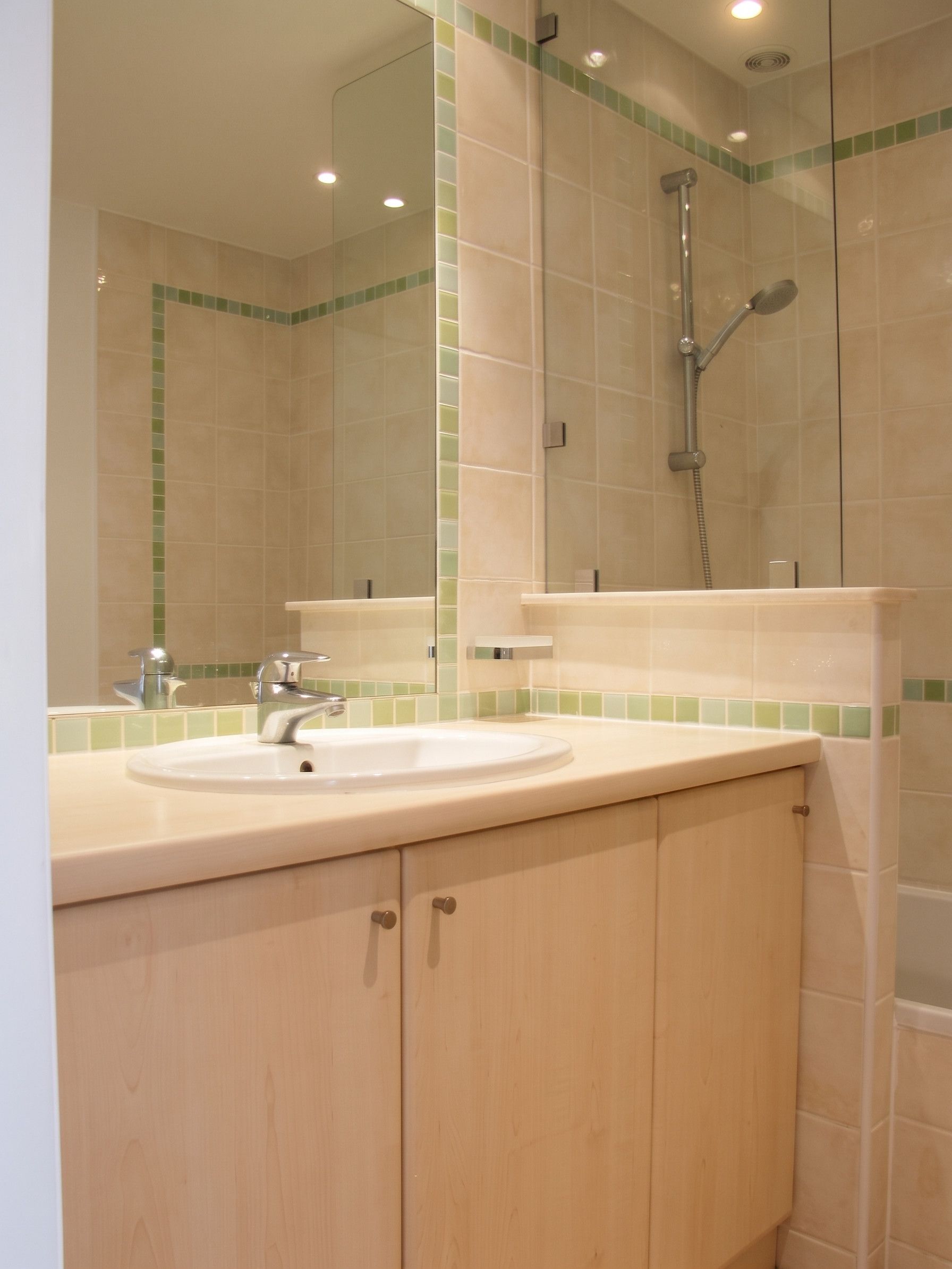 A bathroom with a sink, mirror, and shower.