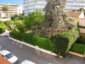 A residential area with a street, parked cars, and a variety of greenery including trees and shrubs. - Homerez - Apartment in Antibes (Antibes)