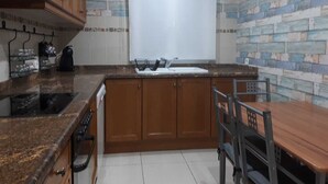 A kitchen with wooden cabinets, a granite countertop, a sink, and a window with blinds.