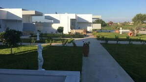 A modern building with a white facade, a well-maintained lawn, and a clear sky.