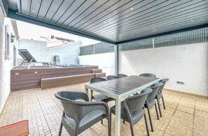 Patio esterno con tavolo e sedie, vasca idromassaggio e una scala che conduce a un piano superiore.