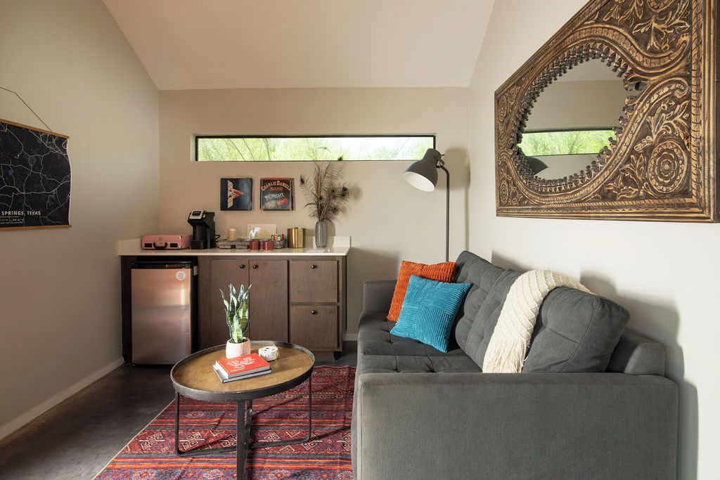 A compact living space with a sofa, coffee table, and a kitchen area with a refrigerator and cabinets.