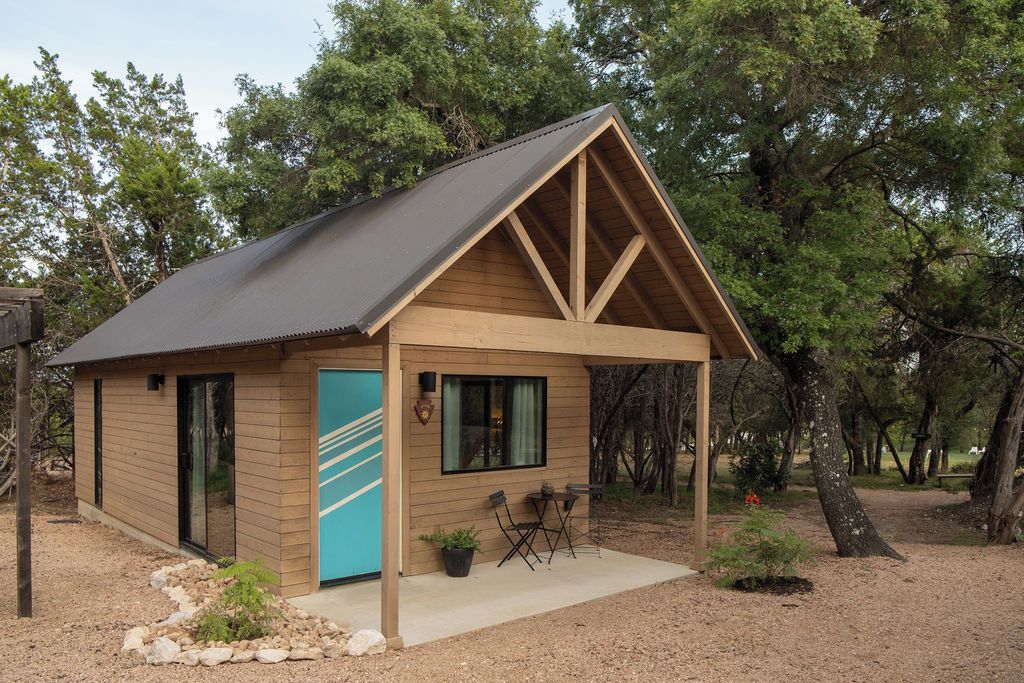 Una pequeña cabaña con techo inclinado, una puerta con franja azul y una ventana.