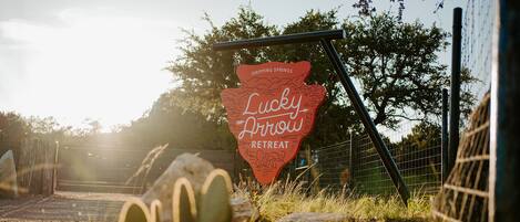Une enseigne pour un centre de retraite appelé « Lucky Draw », avec un design rustique, placée sur un fond de forêt et devant une clôture.