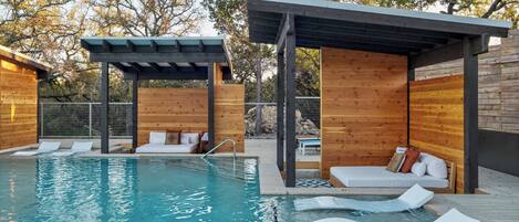 A pool area with wooden structures, lounge chairs, and a pergola.