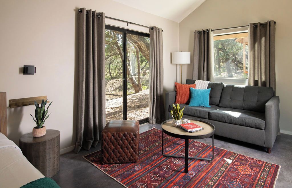 A modern living room with a grey sofa, a round coffee table, and a red patterned rug.