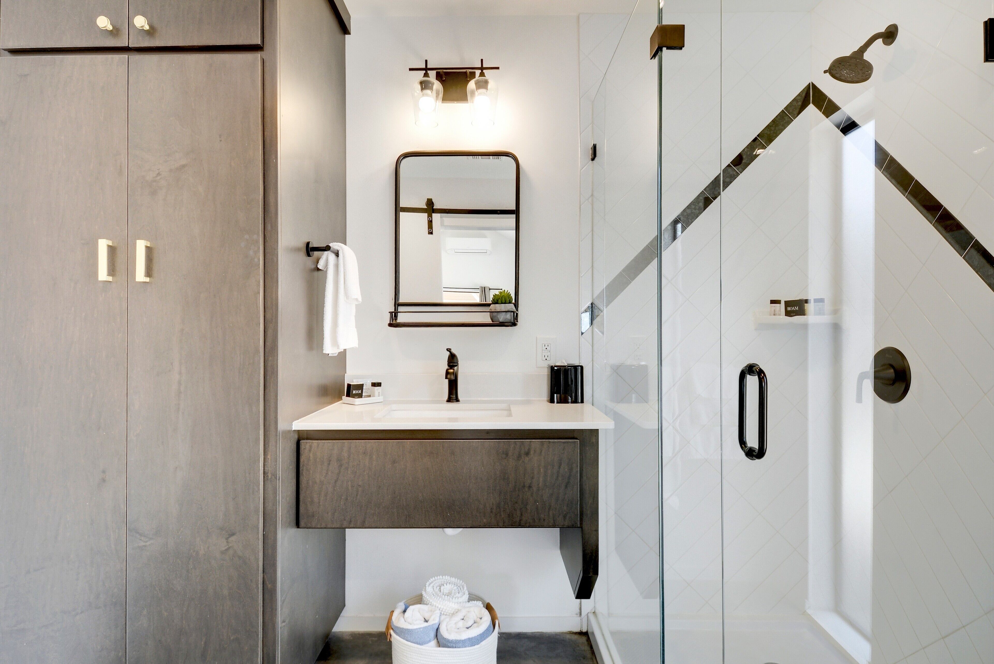 Une salle de bain moderne avec un grand miroir, un lavabo et un espace douche.