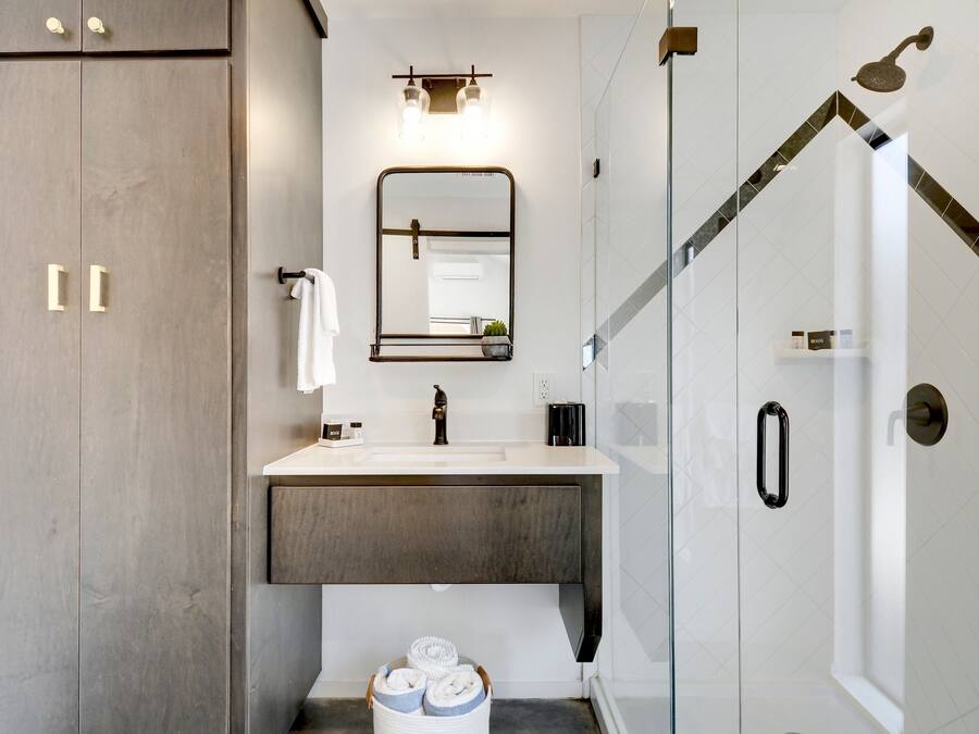 Une salle de bain moderne avec un grand miroir, un lavabo et un espace douche.
