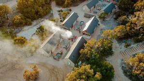 An aerial view of a resort with multiple buildings, outdoor seating areas, and a visible smoke stack. - Lucky Arrow Retreat - Dripping Springs (Dripping Springs)