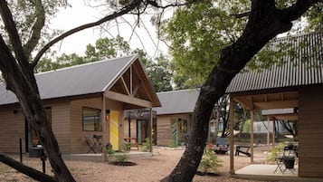 A wooden cabin with a covered patio area, surrounded by trees.