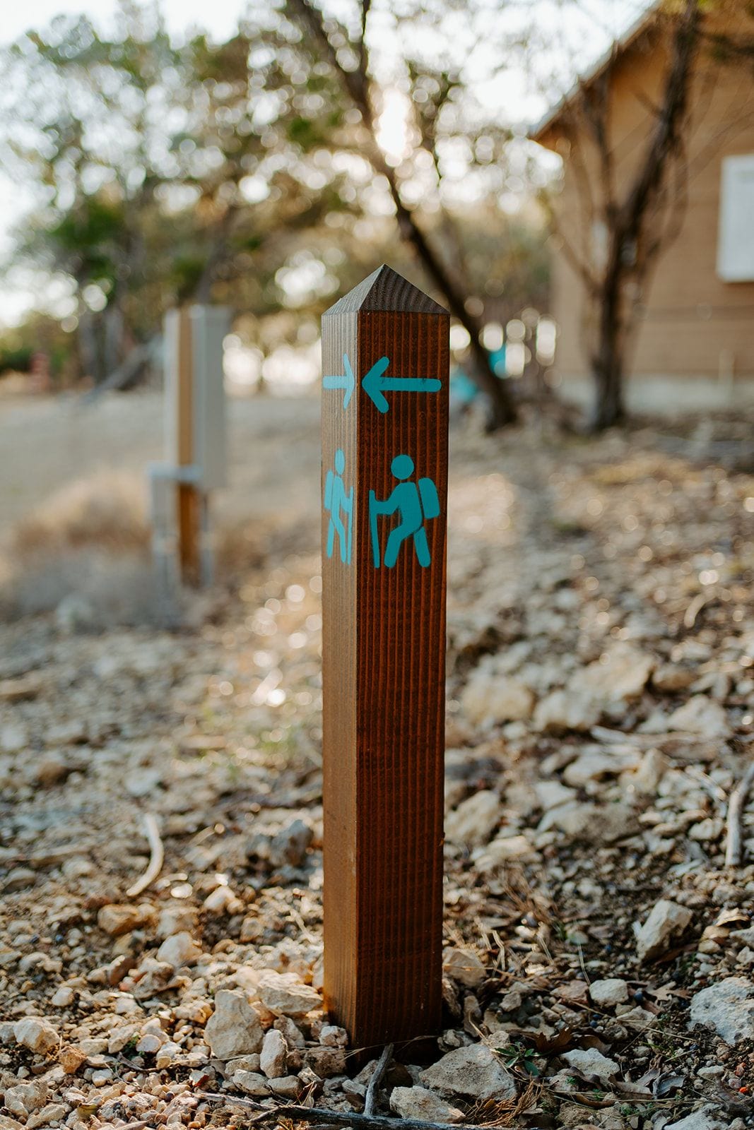 A directional signpost with symbols for hiking and a left-pointing arrow.