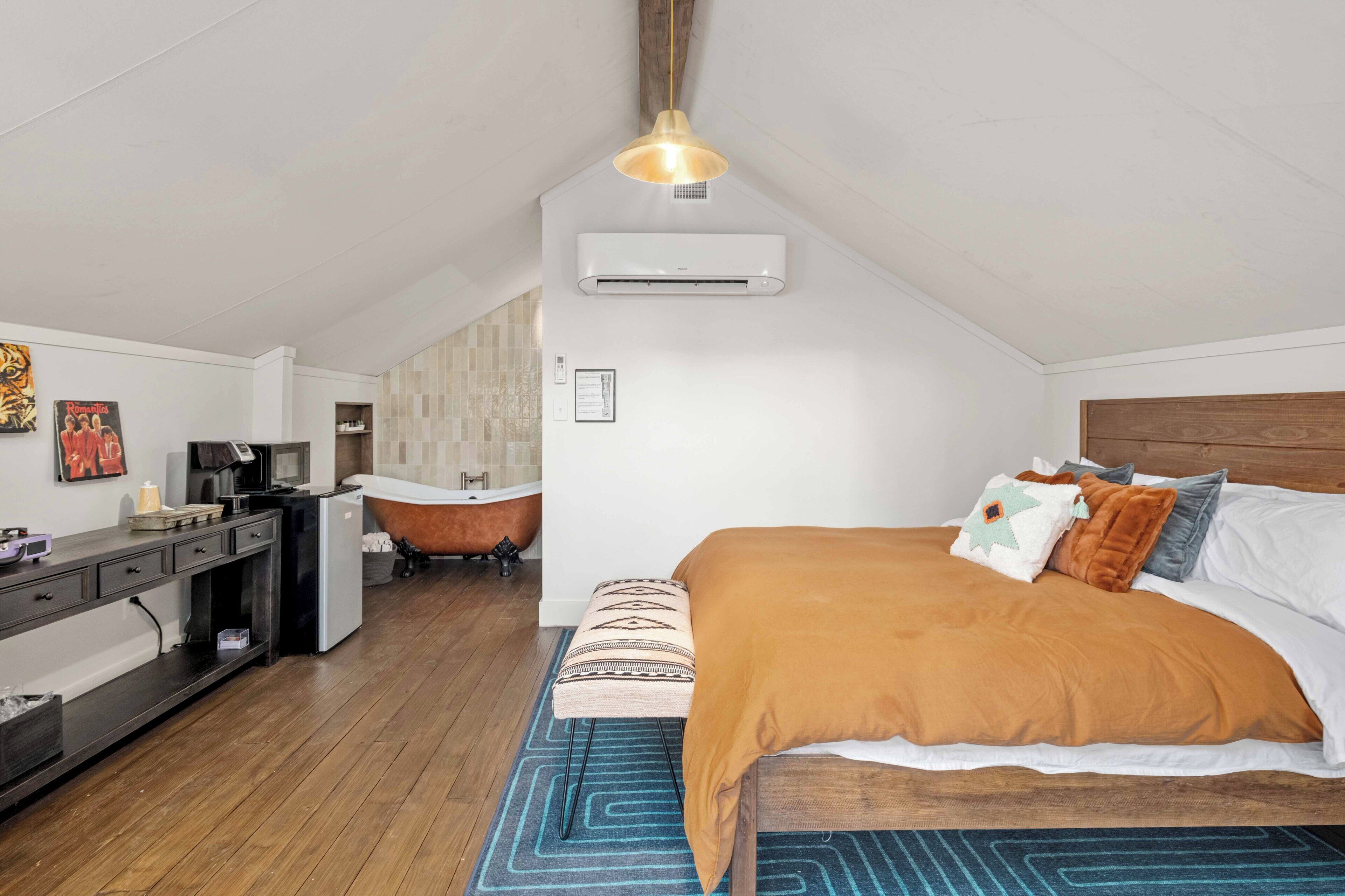 Een gezellige kamer met een bed, een bureau, een stoel en een airconditioning.