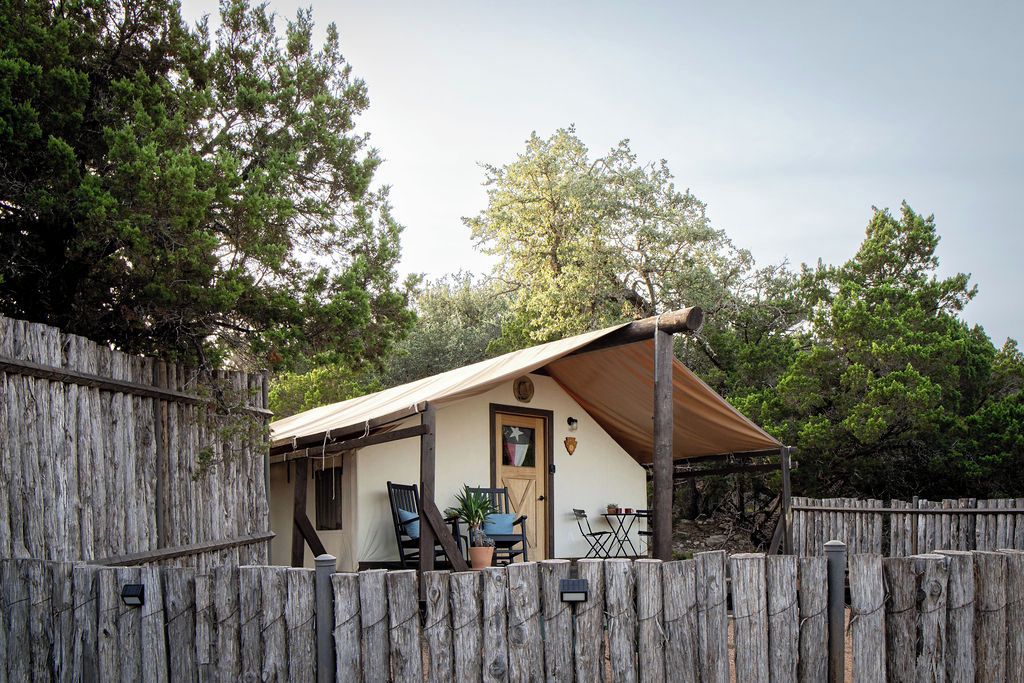 Een rustieke houten chalet met een deur en een klein terras met een tafel en stoelen.