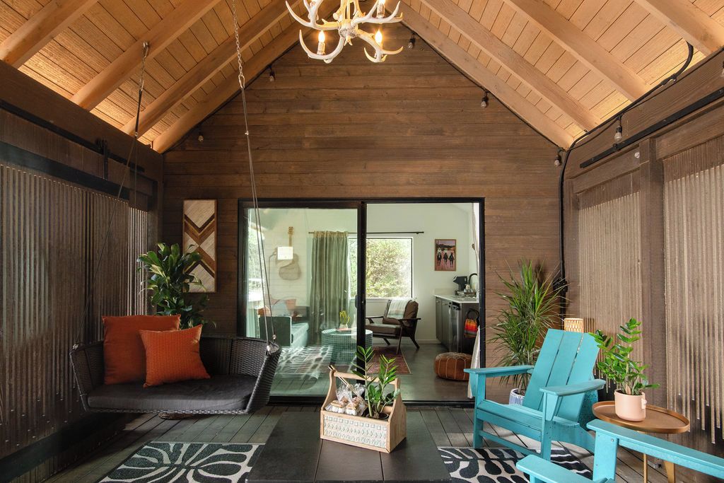 Un intérieur chaleureux avec un plafond en bois, un canapé agrémenté de coussins orange, un fauteuil bleu et une petite table sur laquelle est posée une plante.