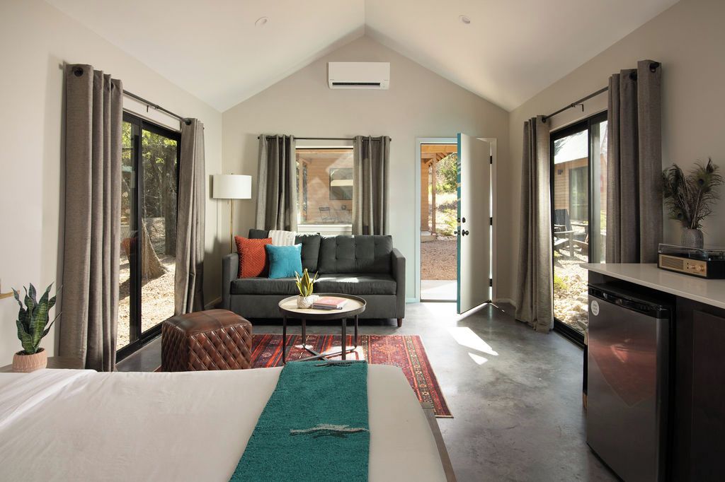 Una habitación de hotel moderna con cama, sofá, zona de comedor y cocina.