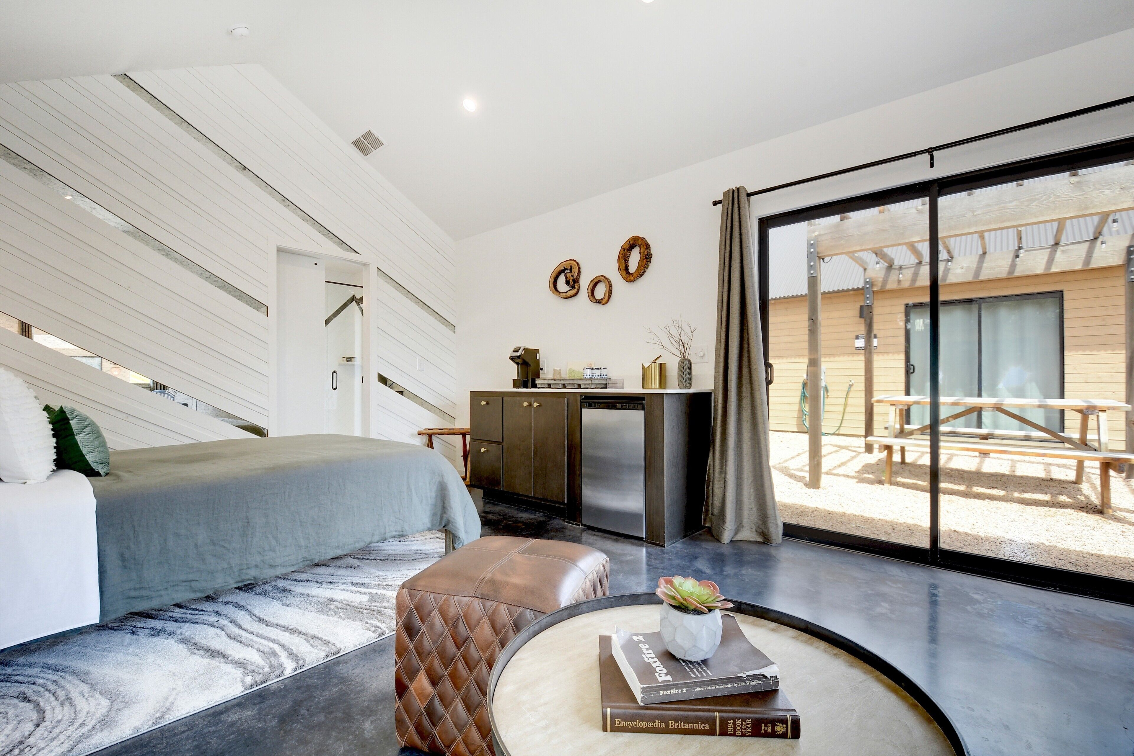A modern bedroom with a bed, a desk, and a view of the outdoors.