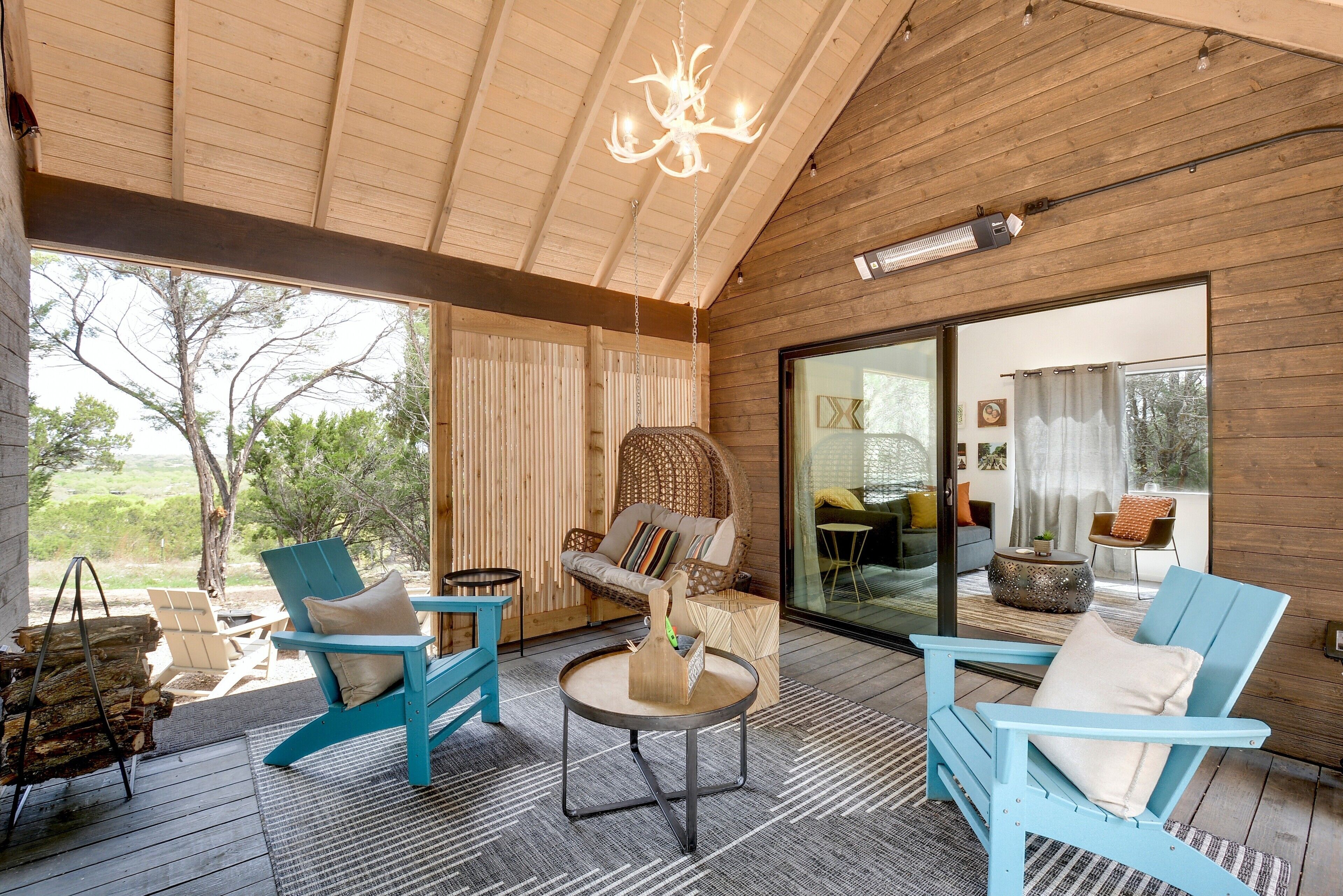Una habitación amplia con paredes de madera, un gran ventanal corredero que da a un balcón y un ventilador de techo.