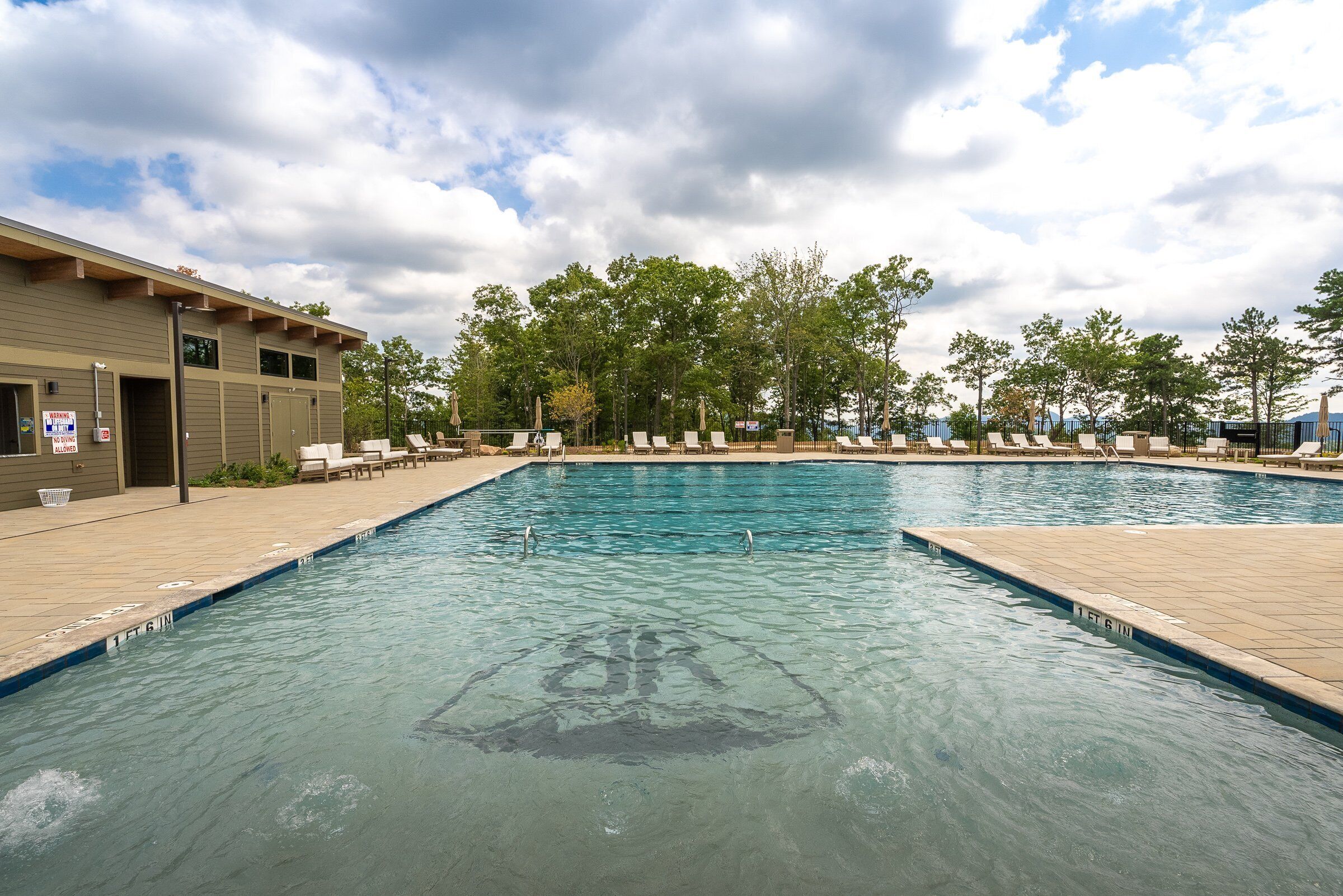 A swimming pool with lounge chairs and a building with a sign.