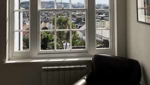 Una habitación con un amplio ventanal que ofrece vistas a la ciudad, un radiador en la parte inferior y un cuadro en la pared.