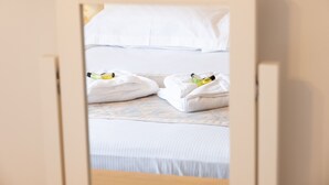 Una habitación de hotel con cama, ropa de cama blanca y toallas dobladas con cuidado.