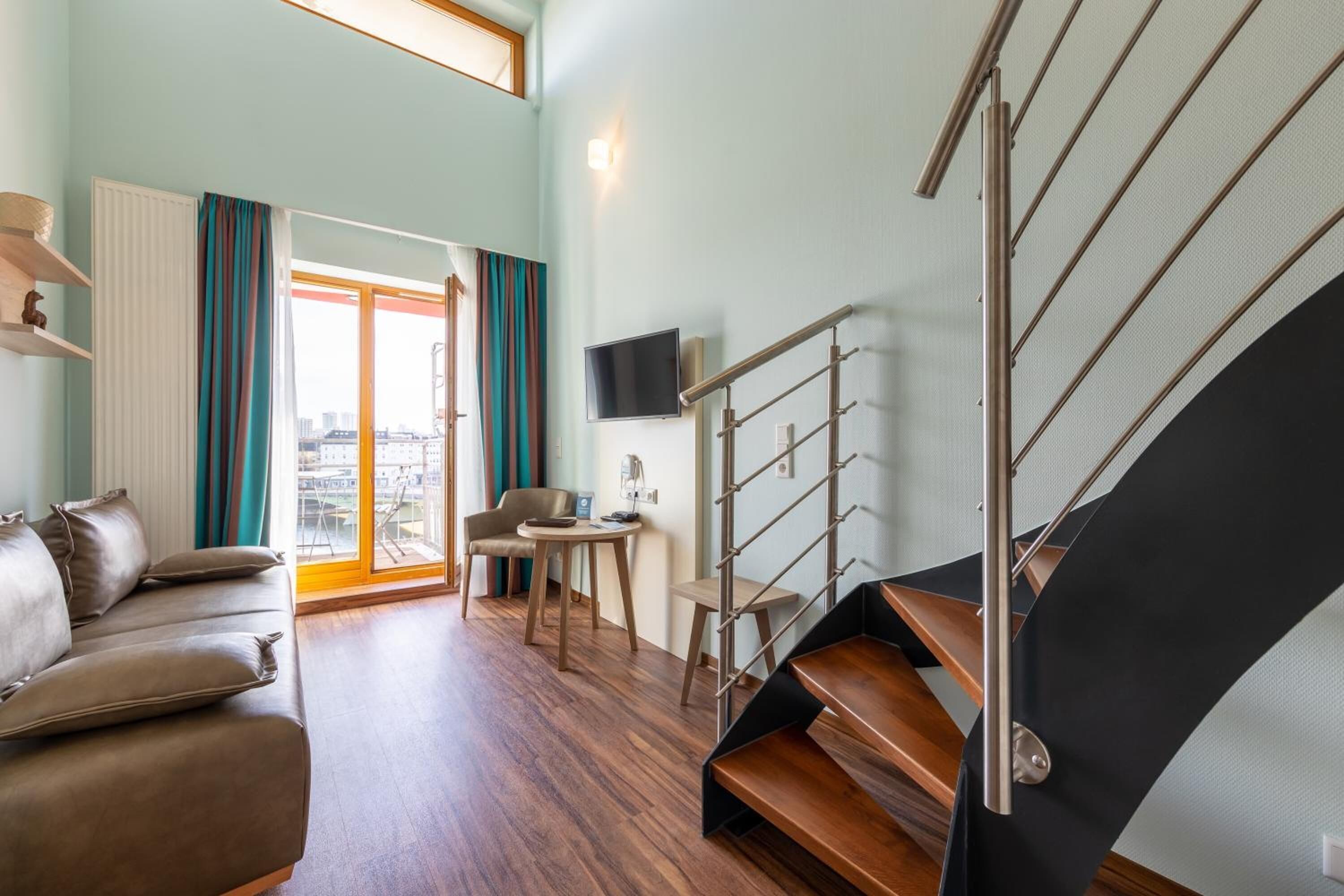 Ein modernes Wohnzimmer mit einer Couch, einem Sessel, einem kleinen Tisch und einer Treppe.