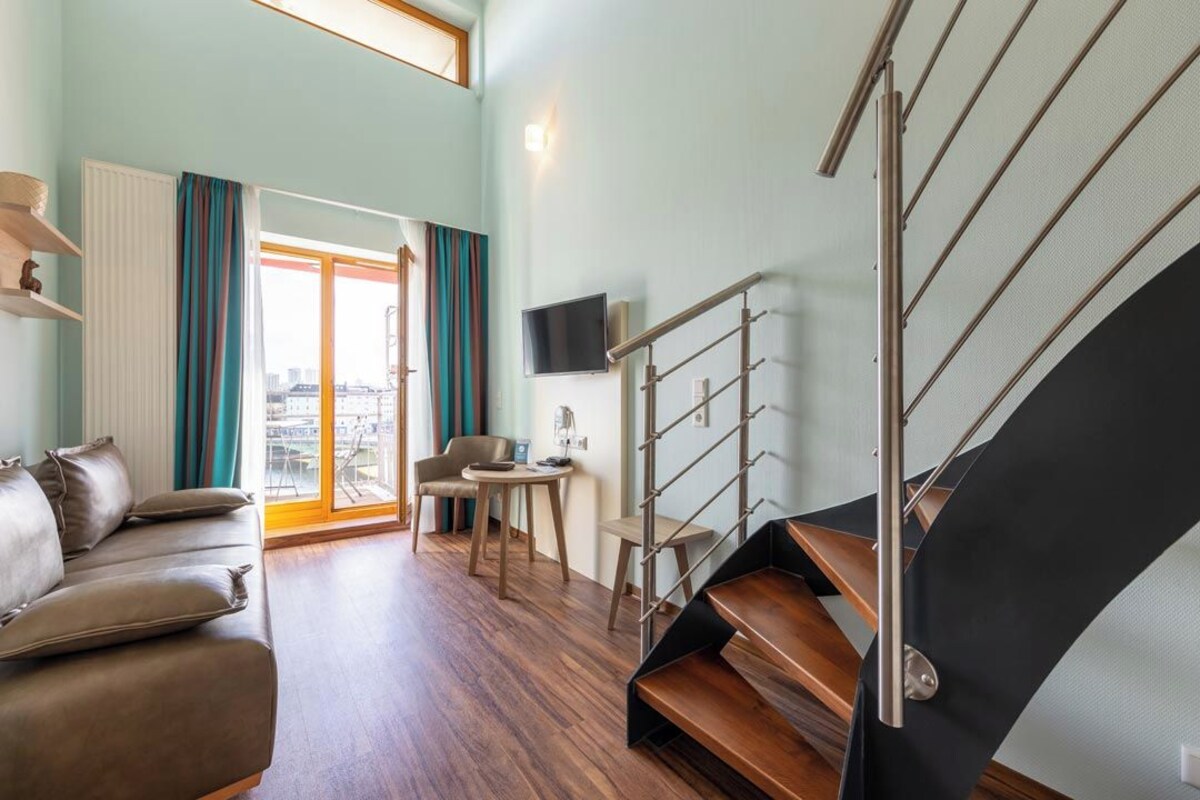 A modern living room with a sofa, a small table, and a staircase.