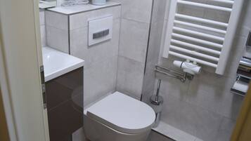 Une salle de bain moderne équipée de toilettes, d’un lavabo et d’une zone douche.