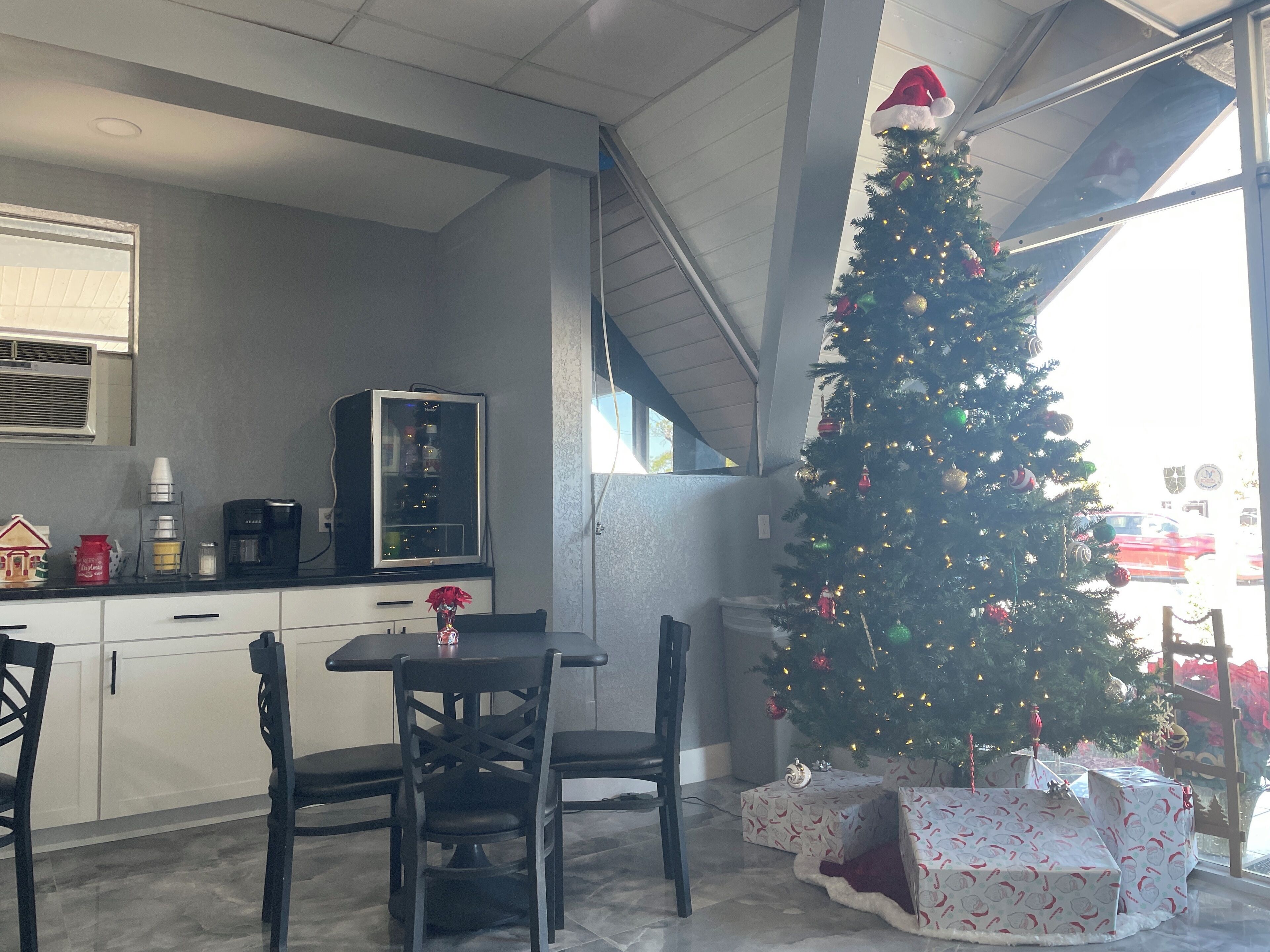 Een moderne keuken met een eettafel, stoelen, een koffieapparaat en een kerstboom.