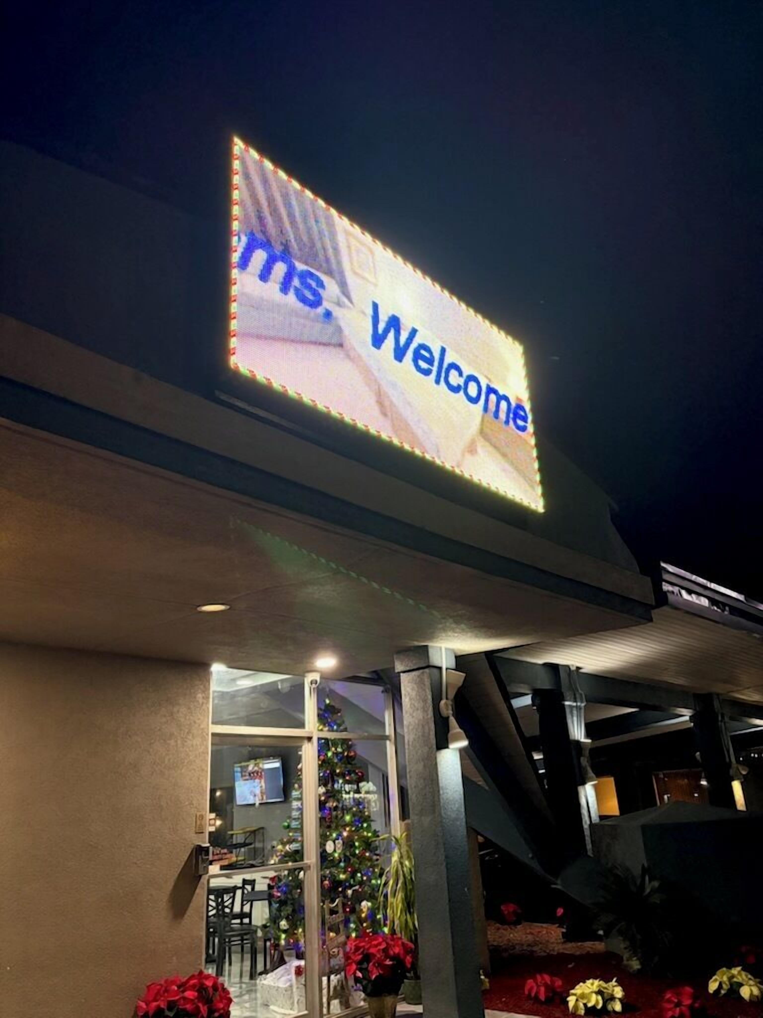 A building entrance with a 'Welcome' sign and a Christmas tree.