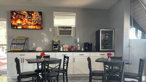 A modern kitchen with a fireplace, a coffee maker, and a TV mounted above the counter. - Regency Inn (Perry)