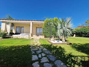 Una casa con un patio, un camino de piedra y una palmera grande.