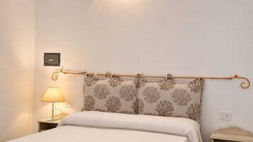 A bedroom with a bed, a nightstand, a lamp, an air conditioning unit, and a decorative wall light.
