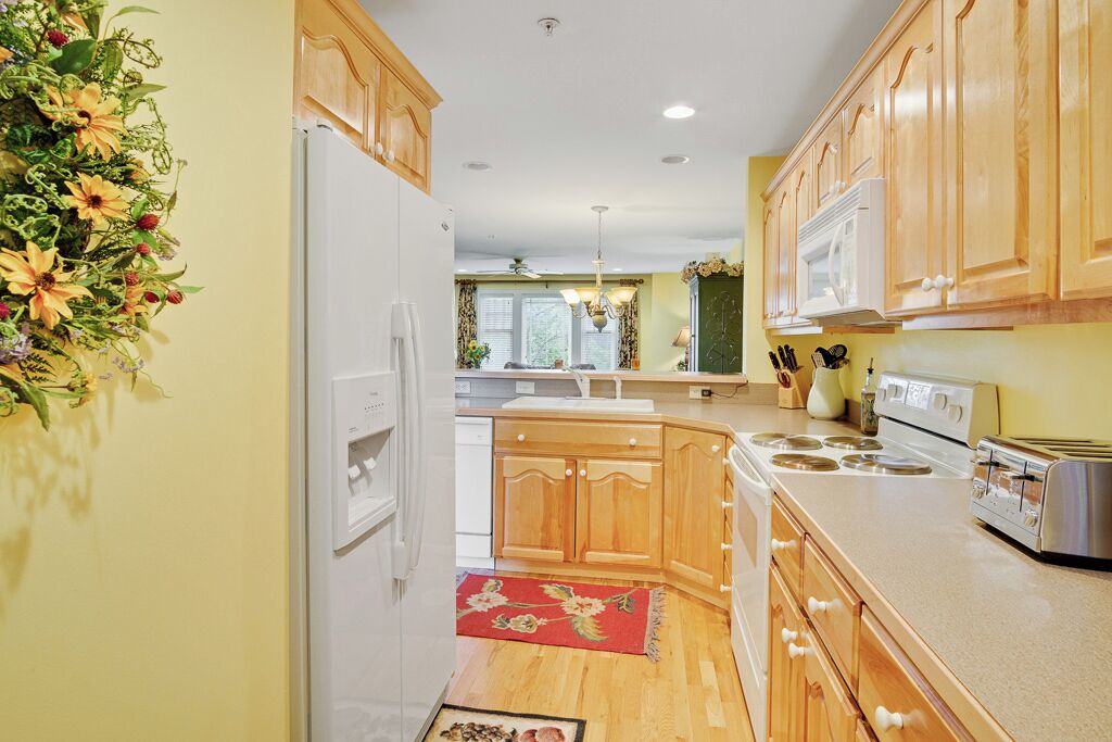 A kitchen with wooden cabinets, a white refrigerator, a stove, and a microwave.