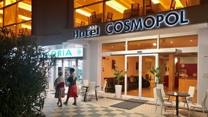 Exterior del Hotel Cosmopol con suelo a cuadros y mobiliario para exteriores.