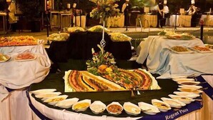 A buffet setup with multiple food stations, a central floral arrangement, and a table with various dishes. - Regent Plaza Hotel & Convention Centre (Karachi)