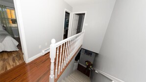Een trap met witte balustrades, een houten vloer en een kleed aan de onderkant.