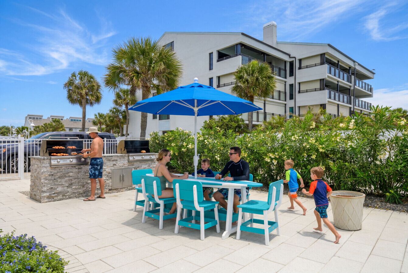 A patio with a grill, outdoor seating, and a building in the background.