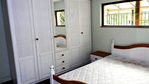 Een slaapkamer met een bed, een kledingkast, een nachtkastje en een raam.