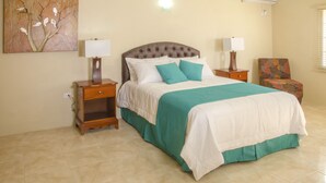 Un dormitorio con una cama grande, dos mesitas de noche con lámparas, una silla y un aire acondicionado instalado en la pared.