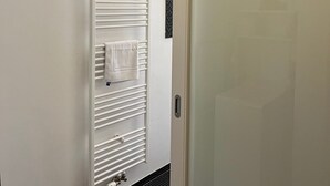 Pared blanca con un toallero empotrado y una toalla colgada.