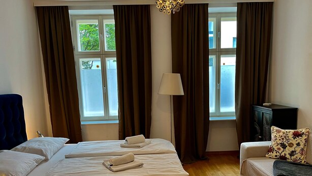 Una habitación de hotel con una cama grande, un sofá, una lámpara y vistas al exterior a través de la ventana.