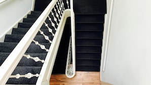 A staircase with black carpeted steps and white balusters.