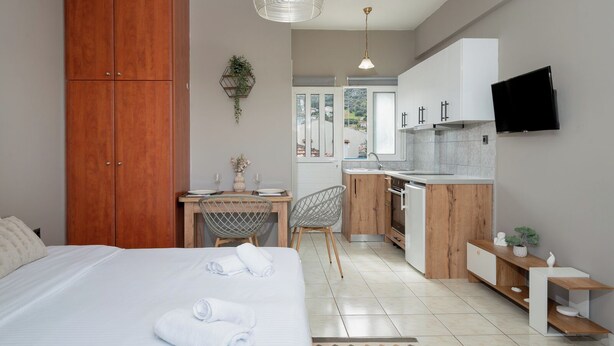 Una habitación compacta con una cama grande, una mesa de comedor y una kitchenette.