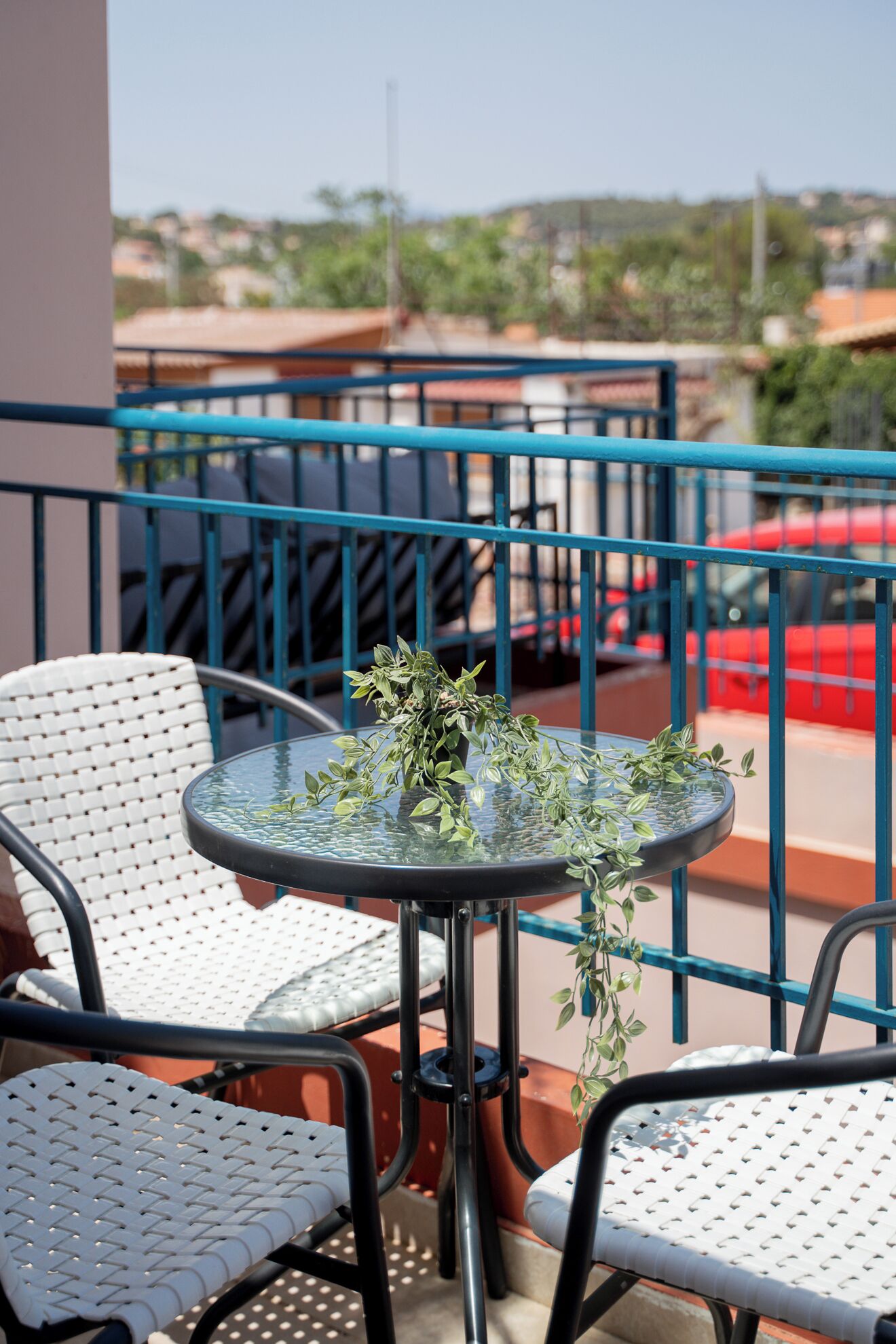 A balcony with a round table and two white wicker chairs.