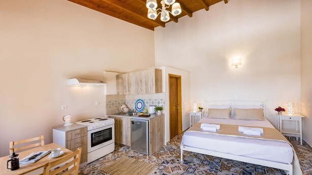 Une chambre compacte comprenant un lit, des tables de chevet et une petite kitchenette.