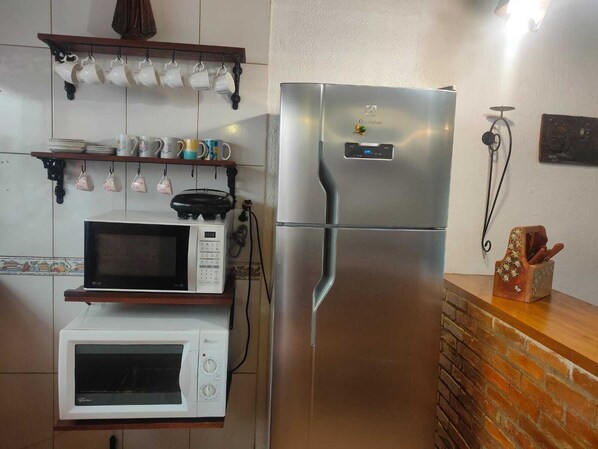 A compact kitchen with a stainless steel refrigerator, a white microwave, and a toaster oven.