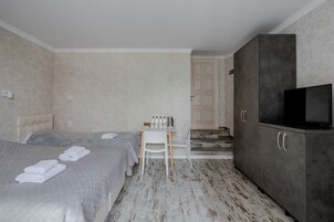Quarto de hotel com duas camas, uma escrivaninha, uma televisão e um guarda-roupa.