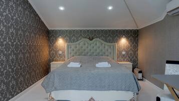 A bedroom with a large bed, two bedside tables, a nightstand, and a desk with a chair.